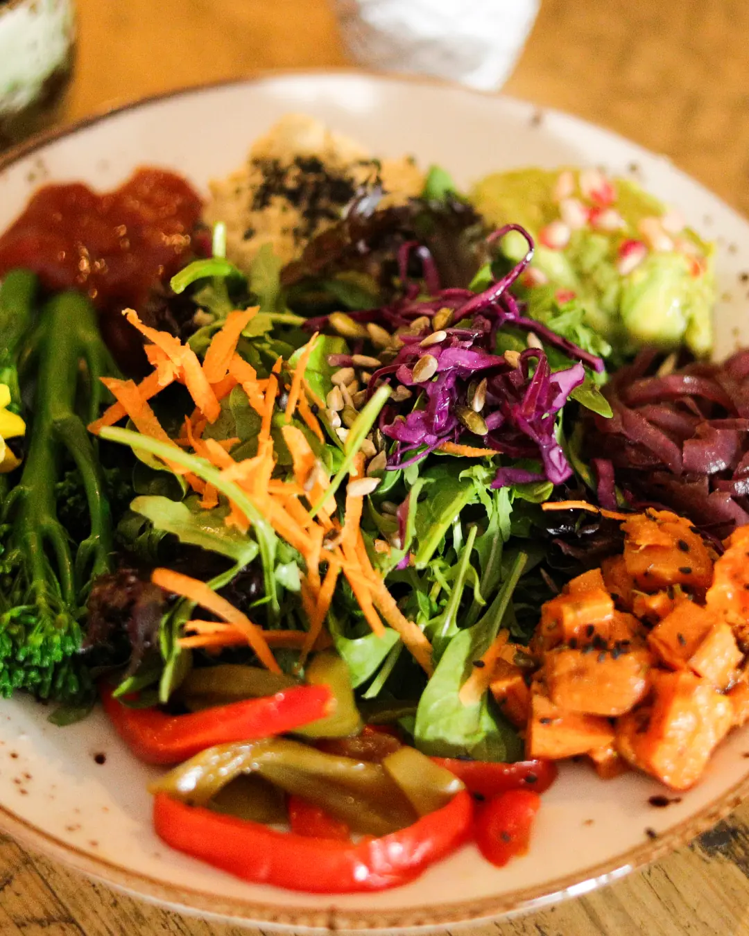 A colourful vegan Buddha bowl filled with fresh roasted vegetables, avocado, and hummus.